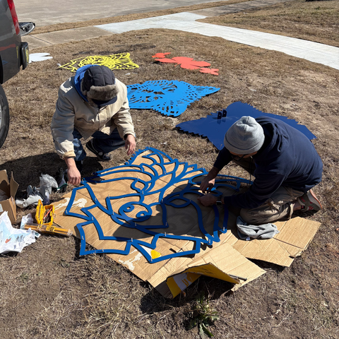 two people assembling a raccoon relief sculpture