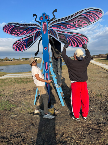 two men assembling the dragonfly relief sculpture